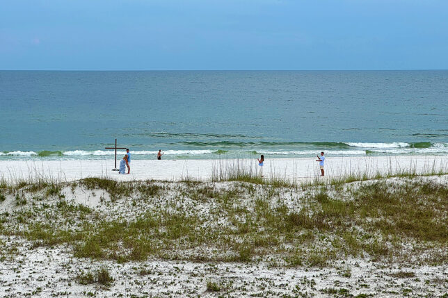 people on a beach with a cross and grass