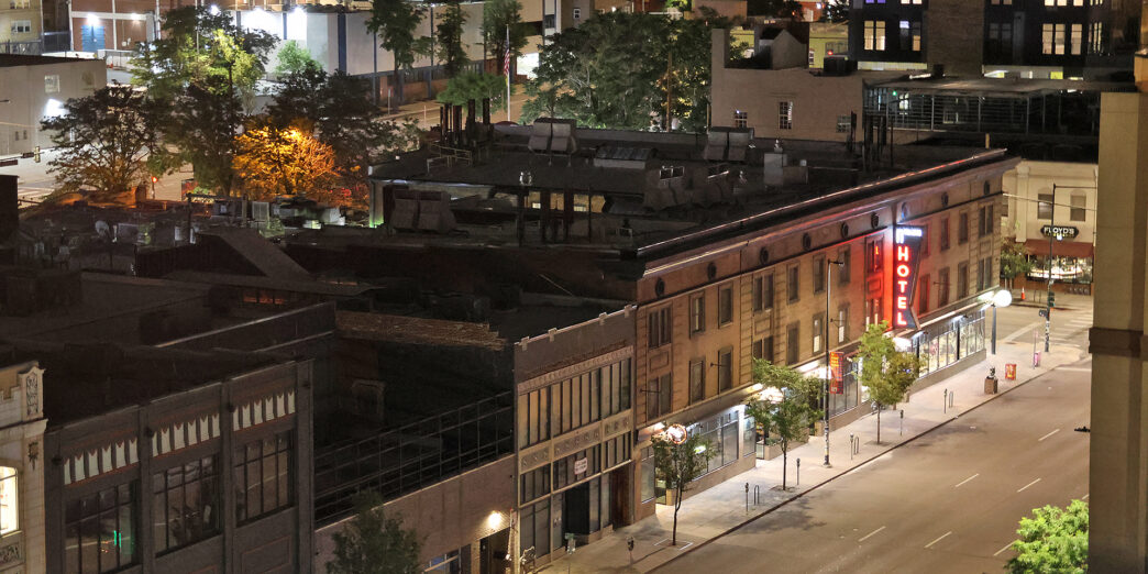 a city street with buildings and trees at night