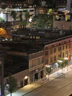 a city street with buildings and trees at night