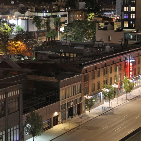 a city street with buildings and trees at night