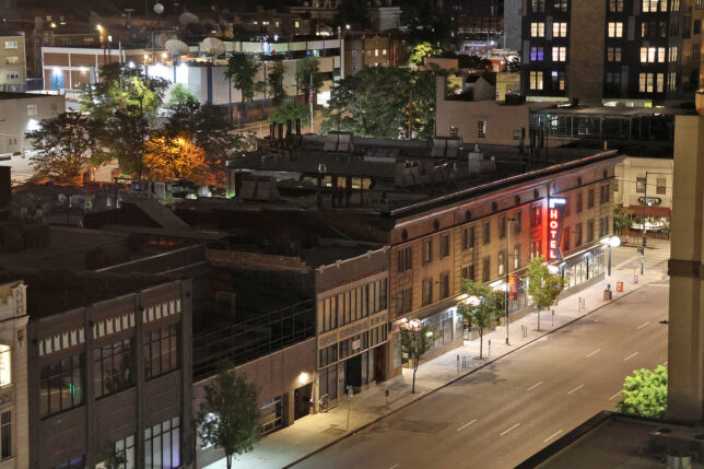 a city street with buildings and trees at night