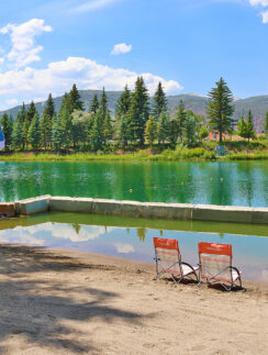 a lake with chairs and a blue umbrella