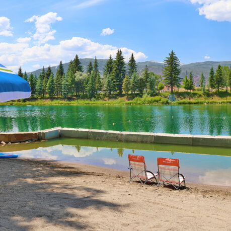 a lake with chairs and a blue umbrella