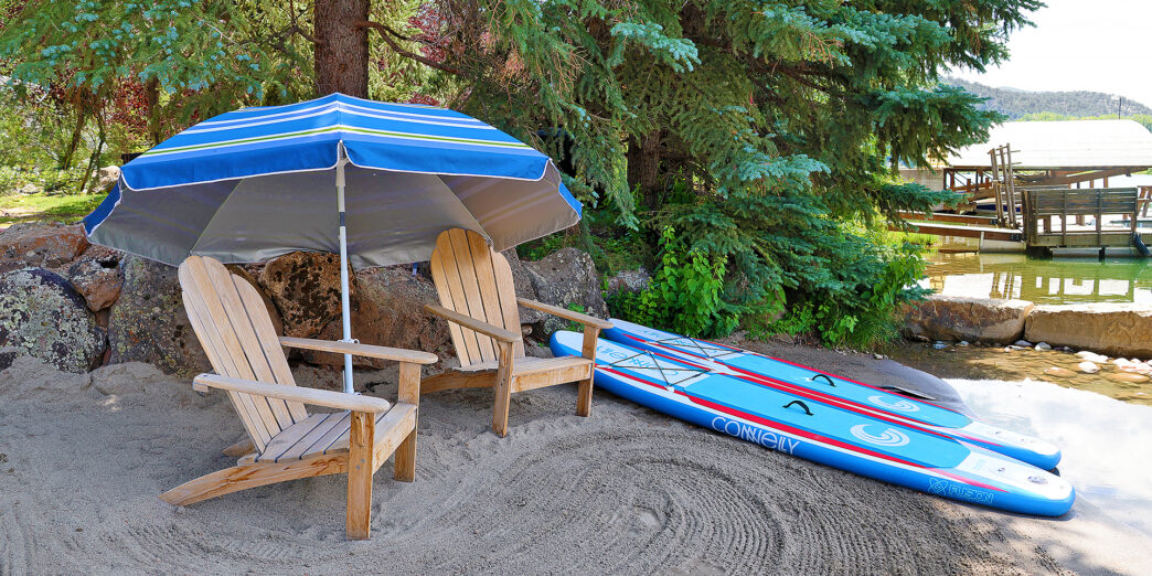 a beach chair and surfboard under an umbrella