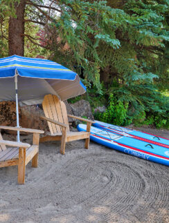 a beach chair and surfboard under an umbrella