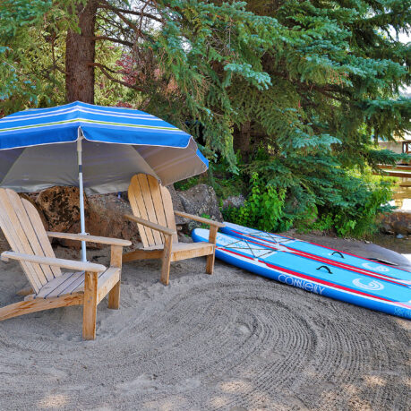 a beach chair and surfboard under an umbrella