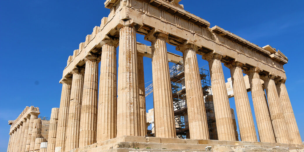 a stone structure with pillars with Parthenon in the background