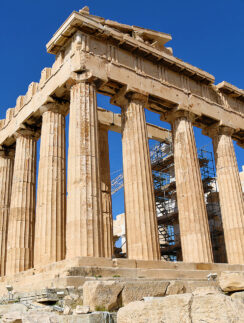 a stone structure with pillars with Parthenon in the background