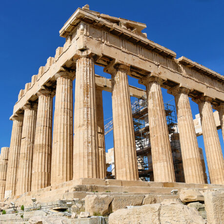 a stone structure with pillars with Parthenon in the background