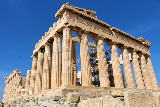 a stone structure with pillars with Parthenon in the background
