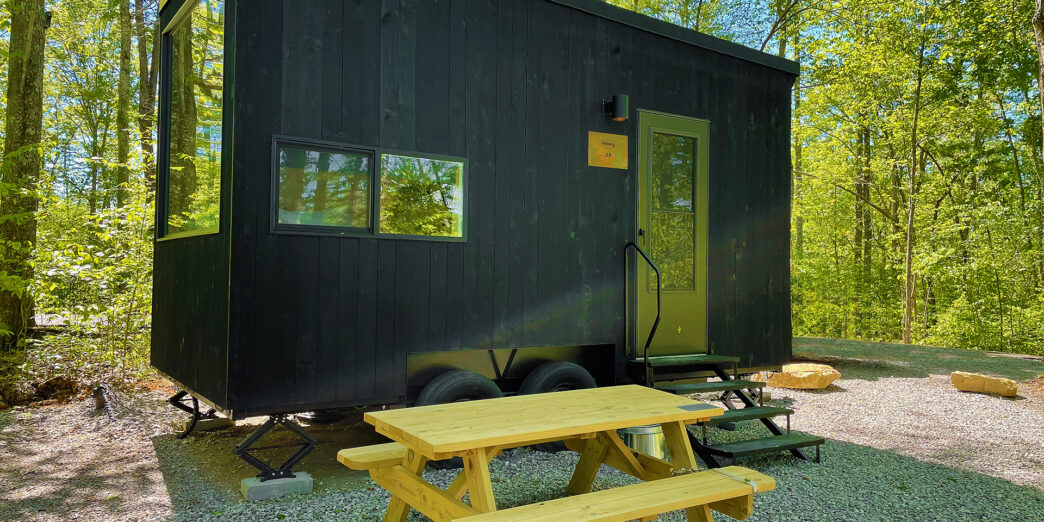 a black trailer with a picnic table in the woods
