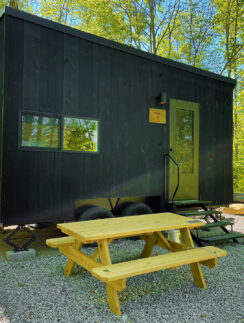 a black trailer with a picnic table in the woods