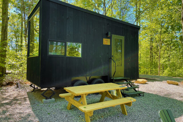 a black trailer with a picnic table in the woods