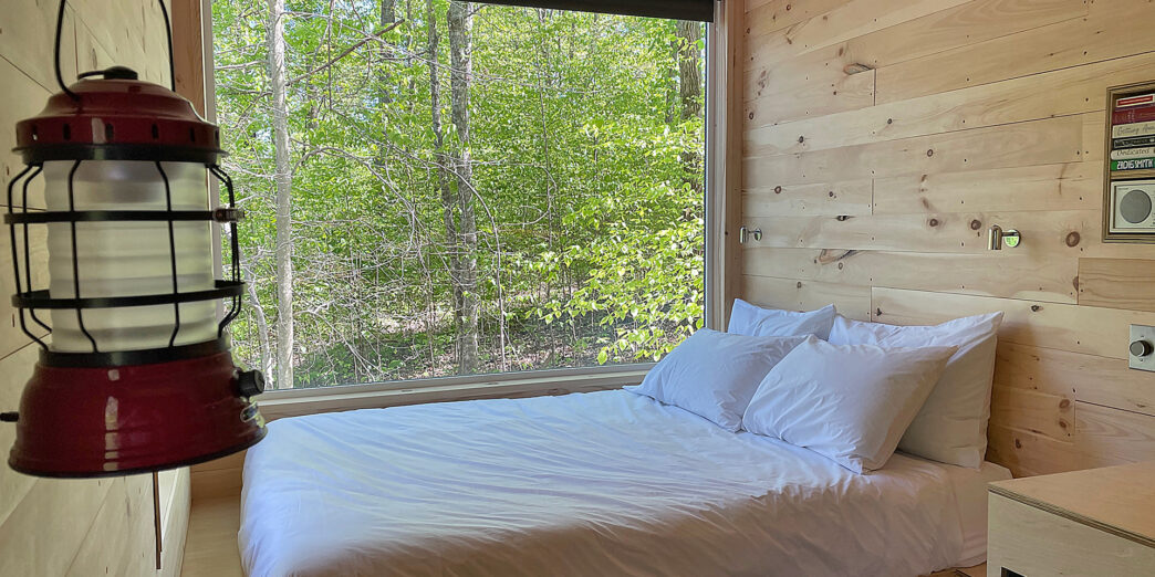 a bed with white sheets and pillows in a room with a window