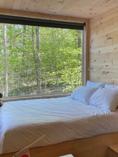 a bed with white sheets and pillows in a room with a window