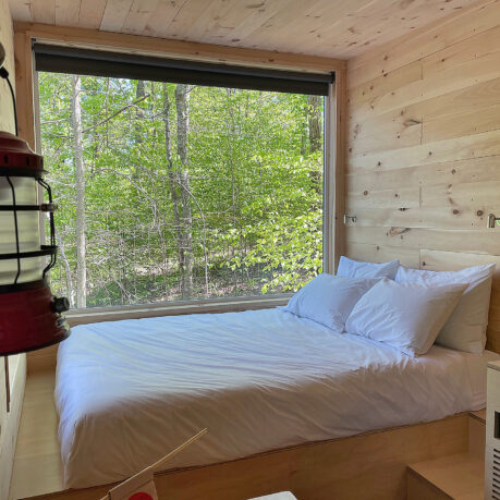a bed with white sheets and pillows in a room with a window