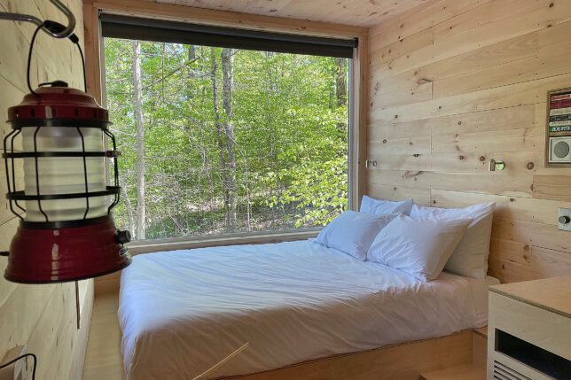 a bed with white sheets and pillows in a room with a window