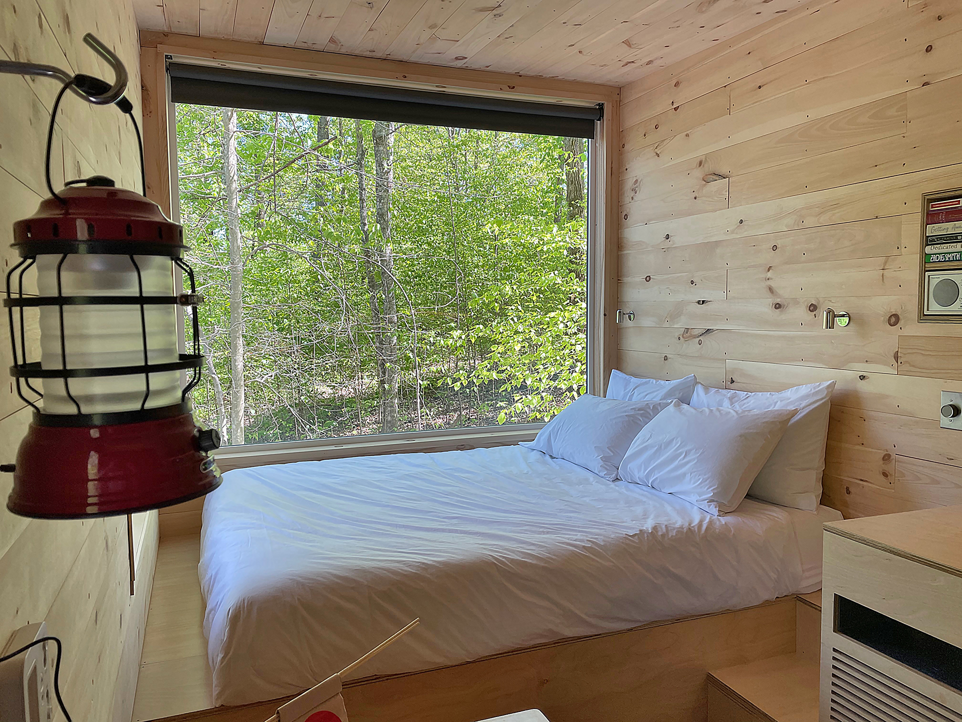 a bed with white sheets and pillows in a room with a window