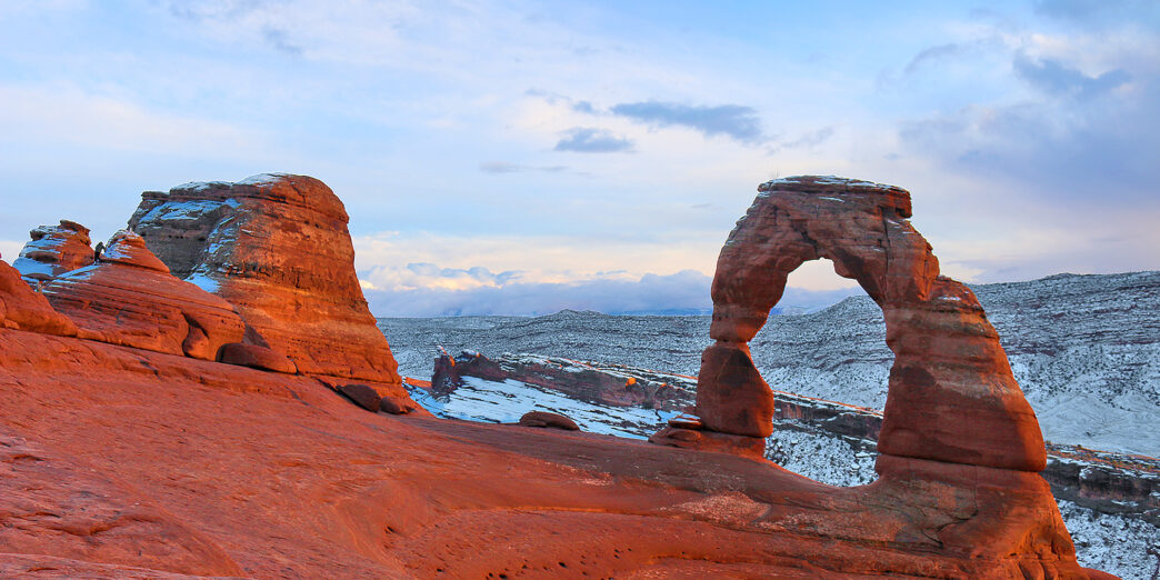 a rock formation in the snow with Arches National Park in the background