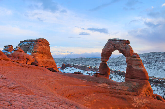a rock formation in the snow with Arches National Park in the background