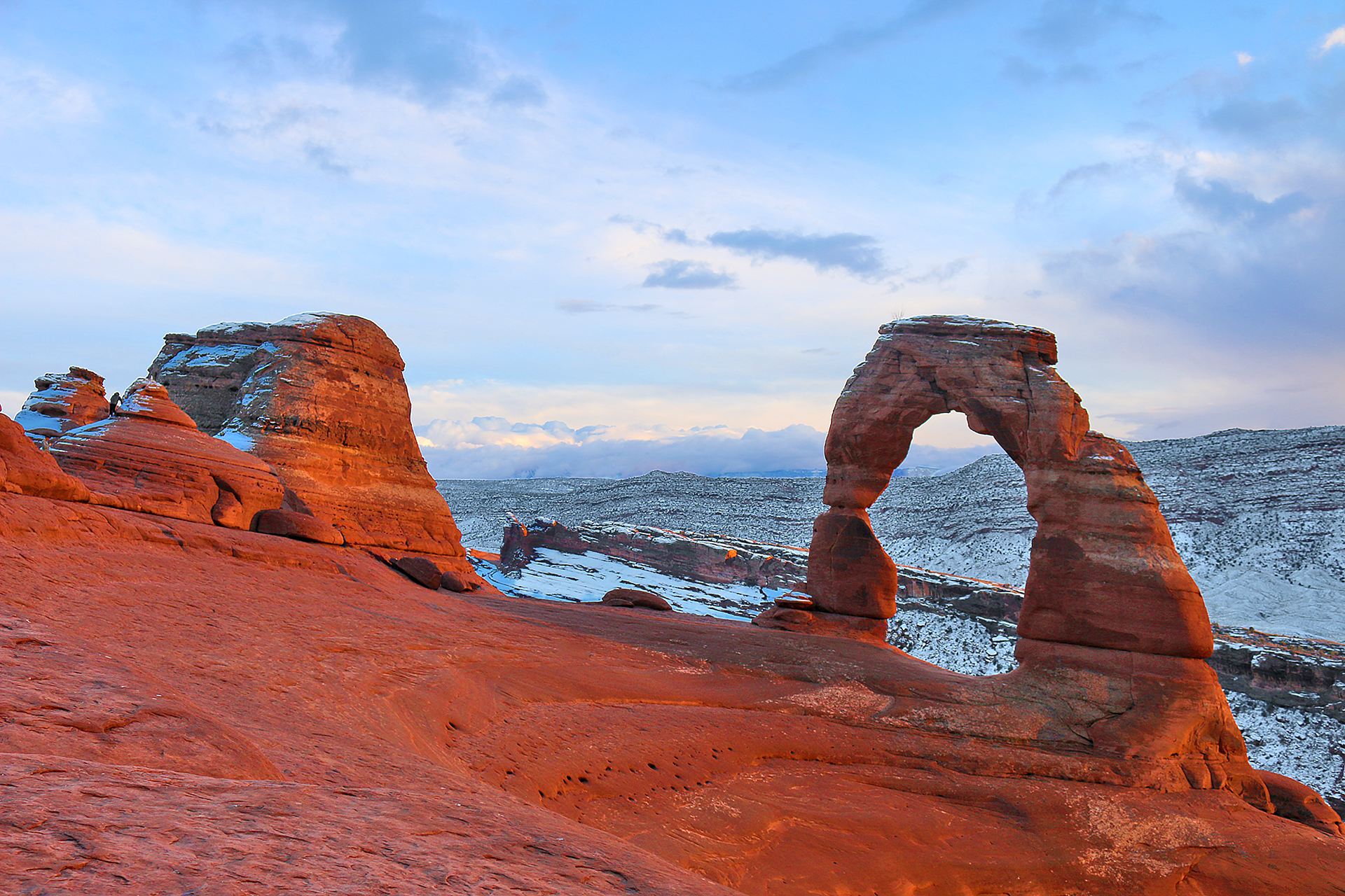 a rock formation in the snow with Arches National Park in the background