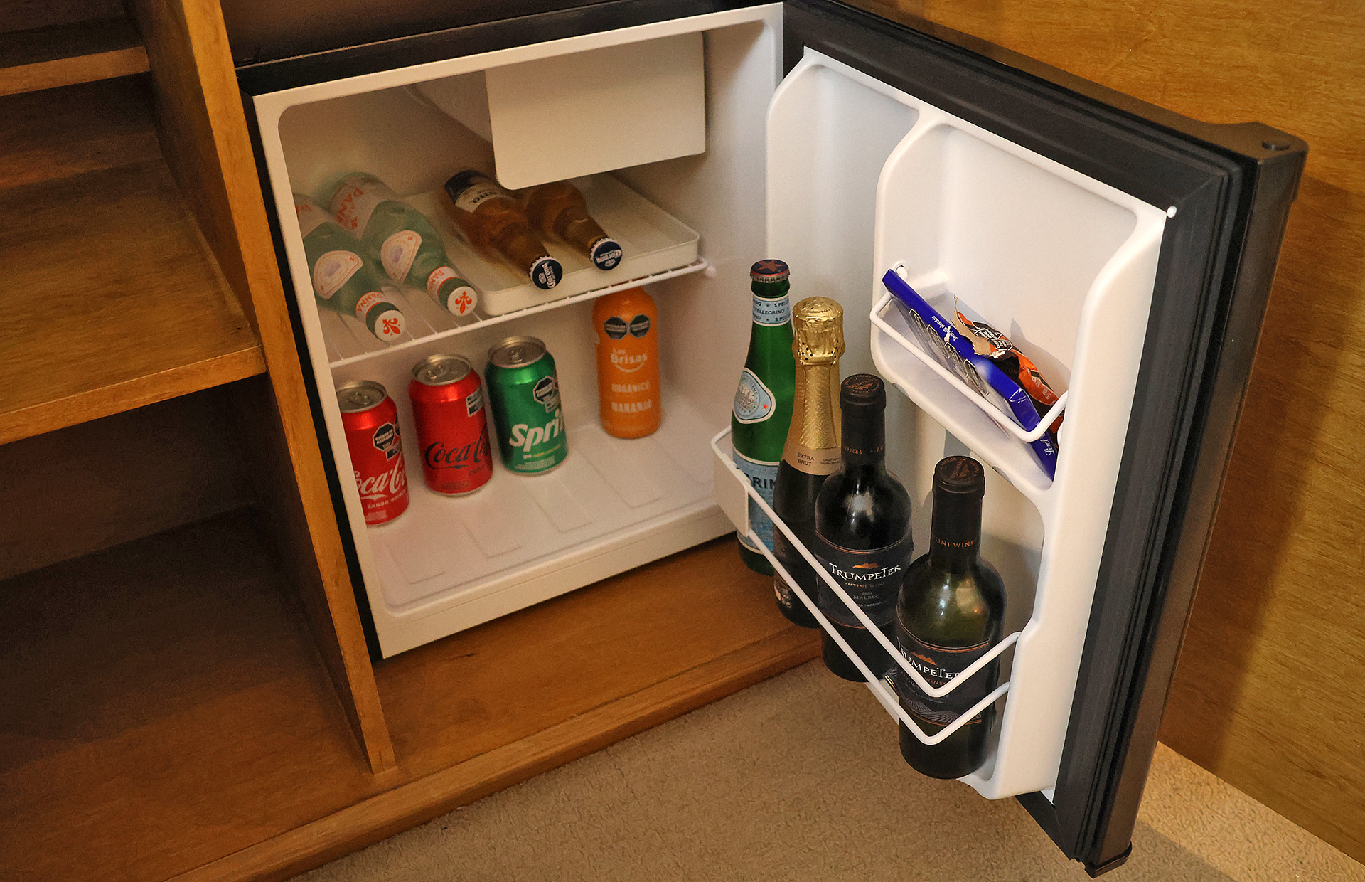 a mini fridge with bottles of beer and a can of soda