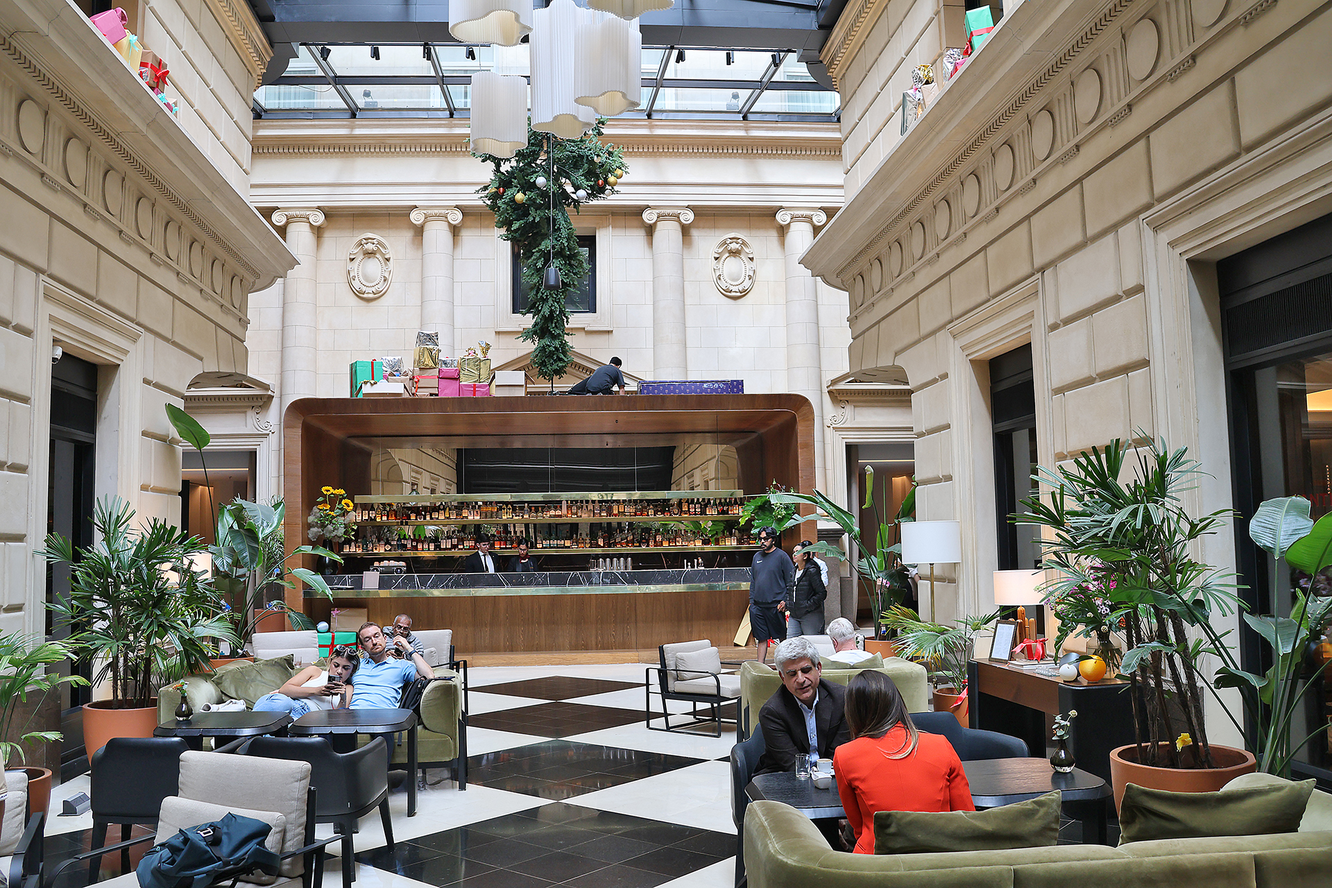 a group of people sitting at tables in a room with a glass ceiling