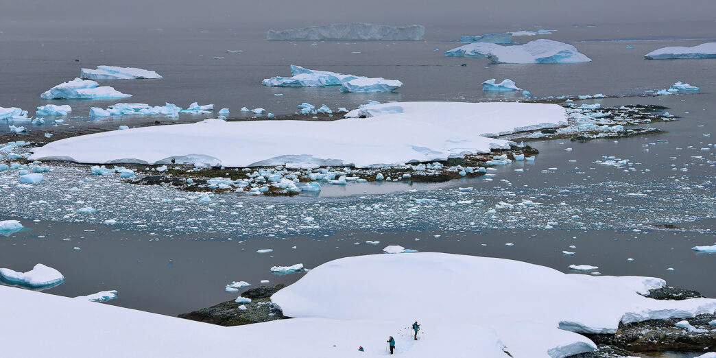 icebergs in the water with people walking on the snow