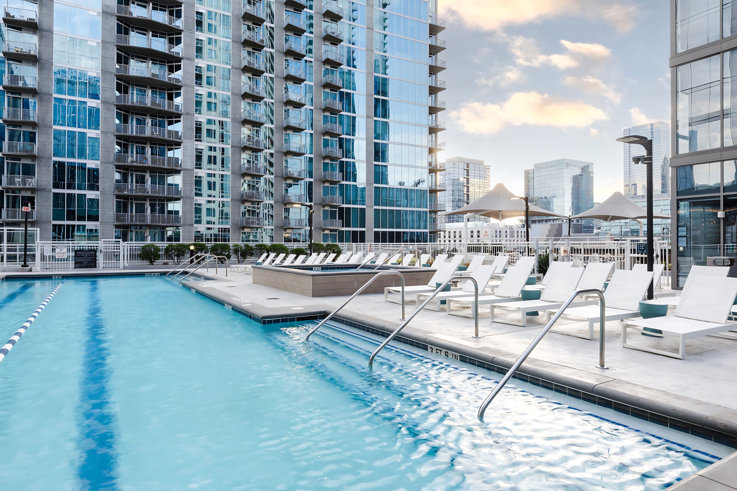 a pool with chairs and a building in the background