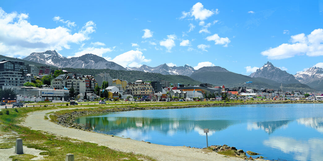 a body of water with buildings and mountains in the background