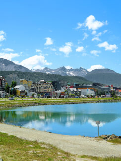 a body of water with buildings and mountains in the background