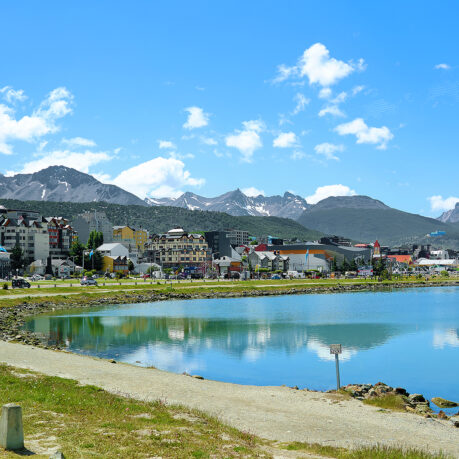 a body of water with buildings and mountains in the background
