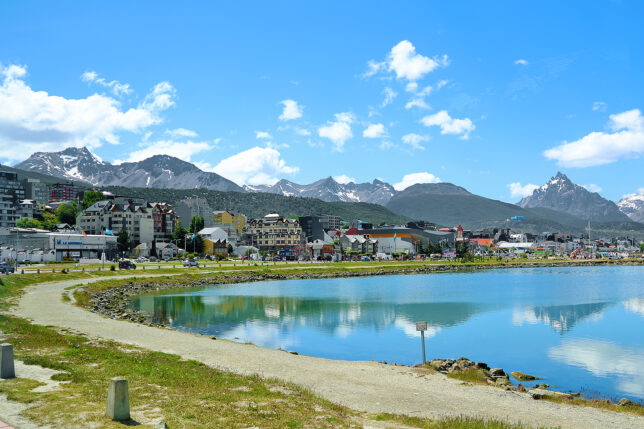 a body of water with buildings and mountains in the background