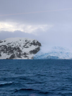 a snowy mountain next to water